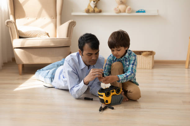 istock Caring hindu dad help little son to fix plastic truck 1300386282