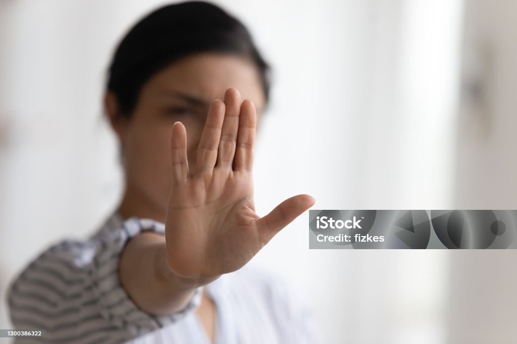 Focus on female palm raising up in stop gesture Stop it. Determined millennial lady strongly resist domestic violence against women gender discrimination bullying abuse. Focus on female palm raising up to camera in forbidding gesture. Copy space Rebellion Stock Photo