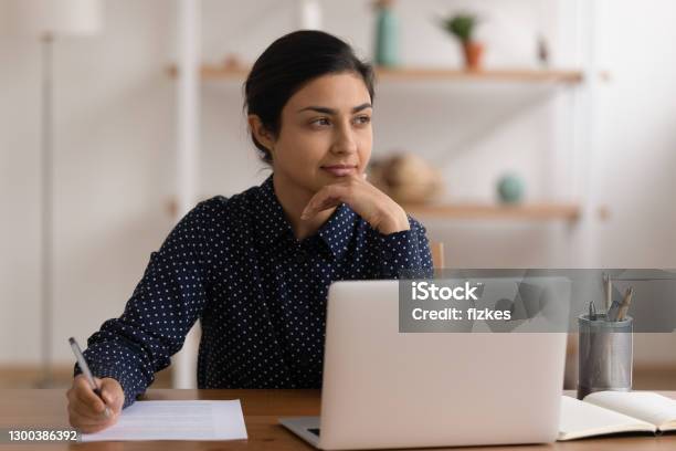 Thoughtful Indian Lady Sitting By Laptop Searching Information Planning Job Stock Photo - Download Image Now