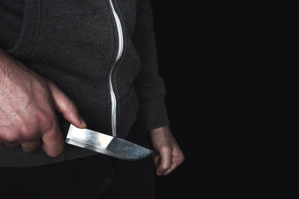 hombre con un cuchillo en la mano de primer plano con el lugar para el texto sobre el fondo negro - cuchillo arma fotografías e imágenes de stock
