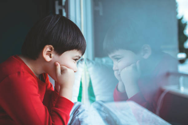 Sad little boy looking out of the window