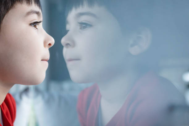Happy little boy day dreaming while looking through window during home quarantine. Shot with high megapixel DSLR camera, canon 5DSR