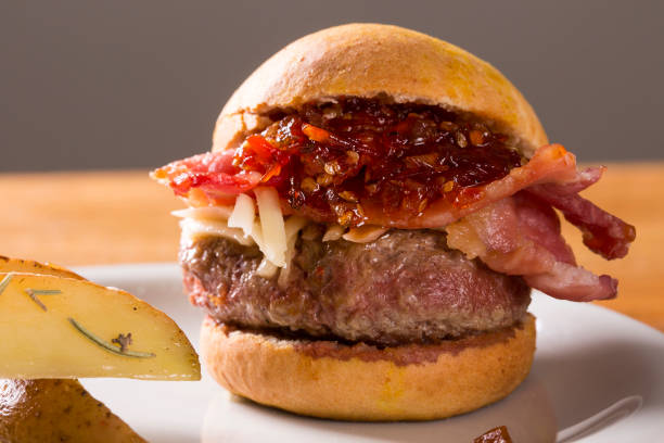 istock Burger with bacon, cheese and pepper on wooden background. Close up 1300391050