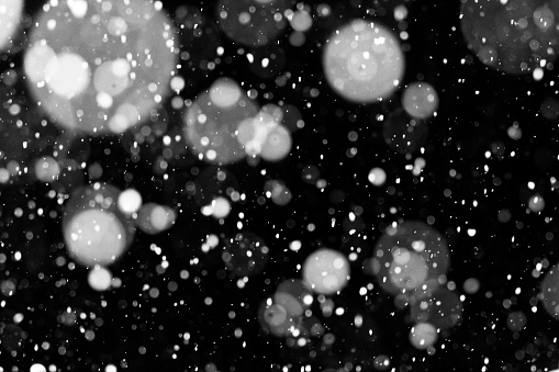 Selective focus of falling snowflakes on black background