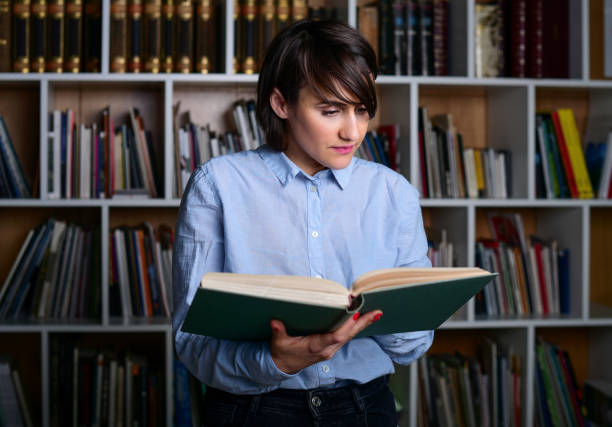 istock Woman at the library reading a book 1300393809