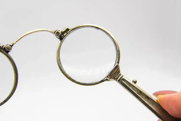 Photo of Hand hold an old vintage lorgnette from the middle of the nineteenth century on the white background