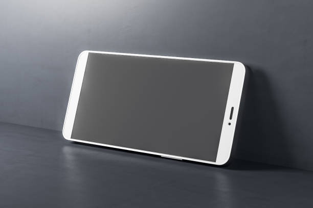istock Black phone with blank screen on cracked concrete floor. 1300398194