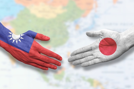 Hands colored like the flags of Taiwan and Japan symbolizing cooperation and friendship. Offering a handshake.