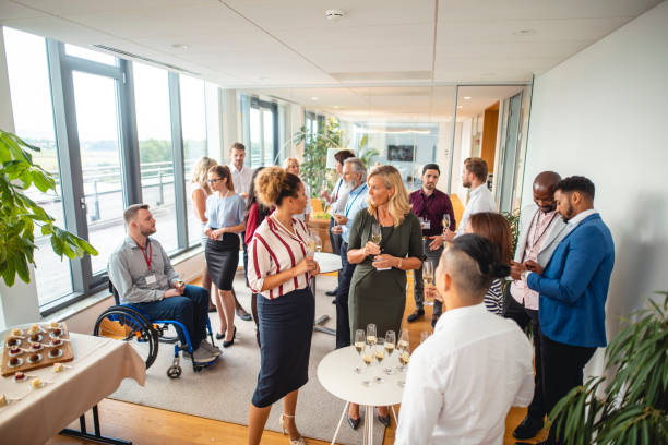 Diverse Businesspeople at New Business Launch Party Elevated wide angle view of diverse businesspeople gathered in modern office lobby for new business launch party. office parties stock pictures, royalty-free photos & images
