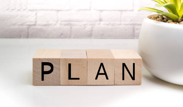istock Wooden elements cubes with letters and the word PLAN on a light table against a brick wall, the concept of business and innovation 1300410857