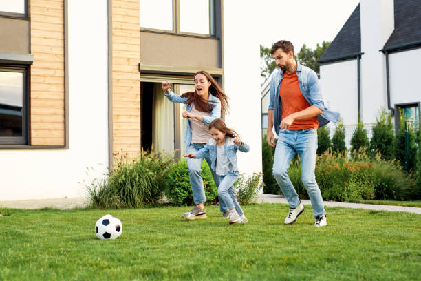 サッカーで遊ぶ笑顔の家族、ボールで走る - family mother outdoors grass ストックフォトと画像