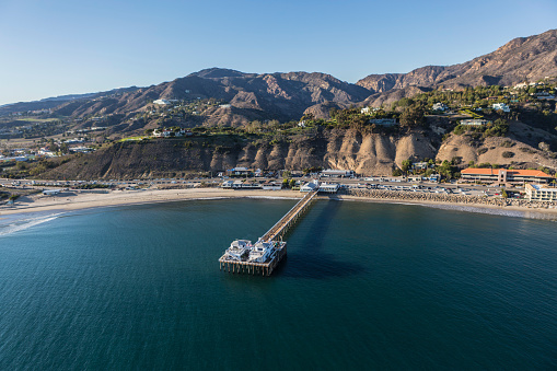 Aerial of the historic Malibu Pier, beaches and the Santa Monica Mountains on the Southern California Pacific Coast.
