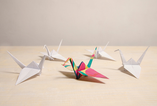 Paper crane birds four made out of white paper and one in the middle colorful , representing leadership and creative thinking