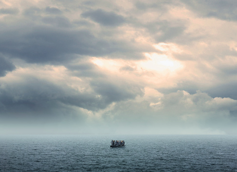 A group of business people standing on a boat searching for a solution as they are stranded in the middle of the ocean.