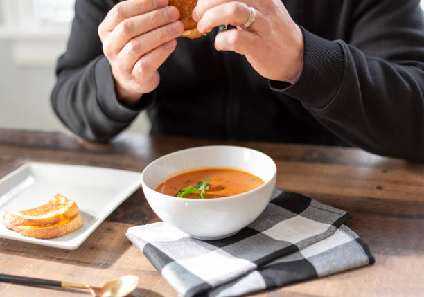 istock Man eating a toasted cheese sandwich with soup for lunch 1300423421