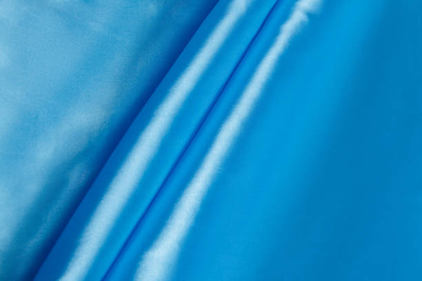 istock Colored blue textile satin fabric folded in folds and waves with highlights and texture 1300424715