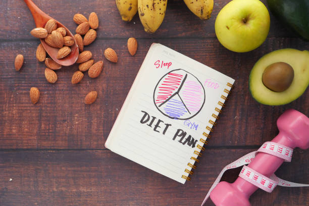 diät-plan mit apfel, mandel, avocado und hantel auf holzhintergrund - weight reduction plan stock-fotos und bilder