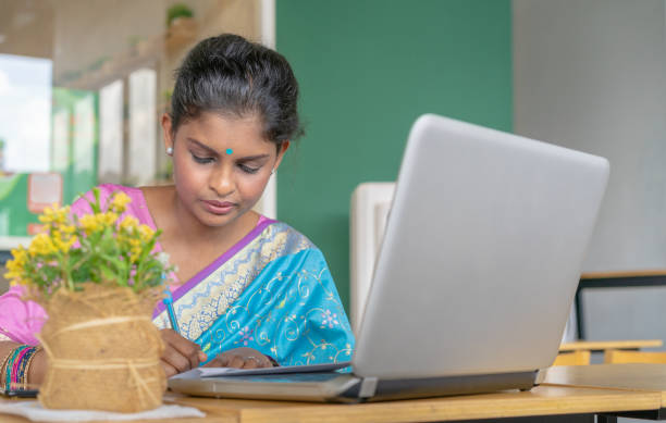 istock Young woman taking notes while having a video call using laptop at home 1300426618