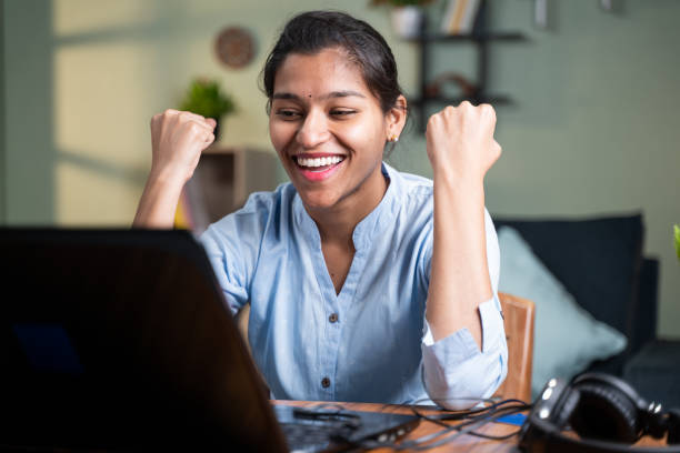 young business woman got overjoyed by good news and started celebrating while working on laptop - Concept of new Job offer or promotion, college admission and loan approvel or won the price money. young business woman got overjoyed by good news and started celebrating while working on laptop - Concept of new Job offer or promotion, college admission and loan approvel or won the price money student result stock pictures, royalty-free photos & images