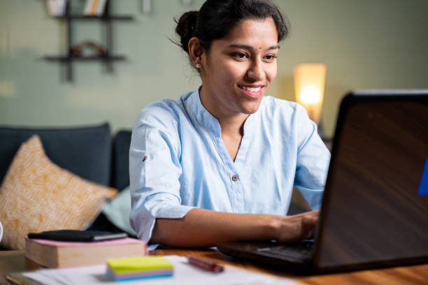 Young business girl busy working on laptop at home in formal wear - concept of professional IT employee during work from home. Young business girl busy working on laptop at home in formal wear - concept of professional IT employee during work from home south asia stock pictures, royalty-free photos & images