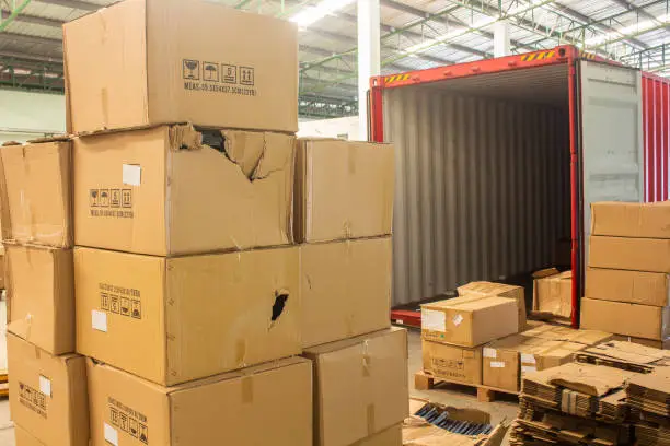 Photo of unloading carton from container and carton damage from loading or transport process.