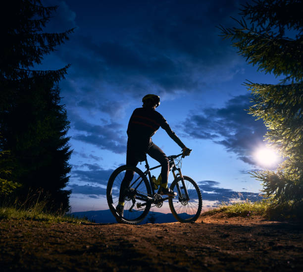istock Male cyclist sitting on bicycle under beautiful night sky. 1300436045