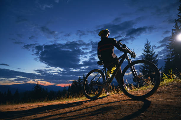 istock Cyclist sitting on bicycle under cloudy night sky. 1300436053