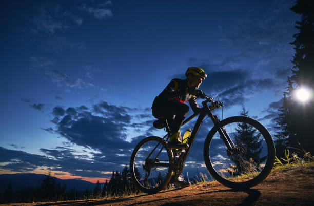 istock Cyclist sitting on bicycle under cloudy night sky. 1300436058