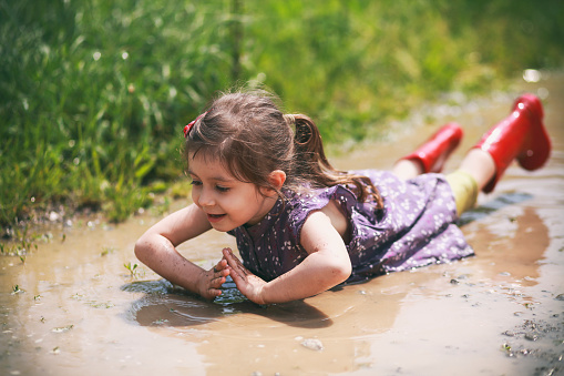 Little girl had an accident and is lying in a puddle. But enjoying it.