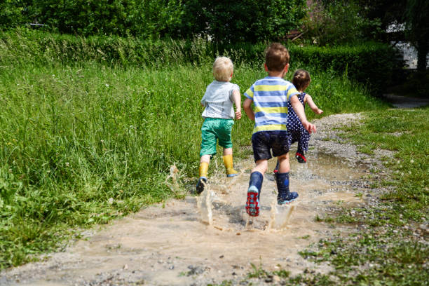 istock Children running on puddles of mudd 1300436866
