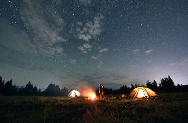 istock Hikers standing near campfire under beautiful starry sky. 1300436929