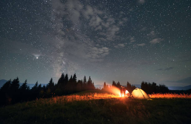 istock Hikers standing near campfire under beautiful starry sky. 1300436931