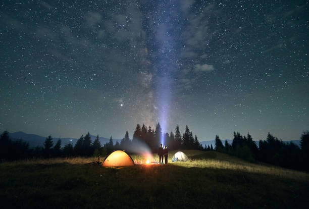 istock Hikers standing near campfire under beautiful starry sky. 1300436932