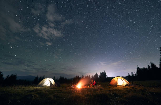 istock Hikers standing near campfire under beautiful starry sky. 1300436948