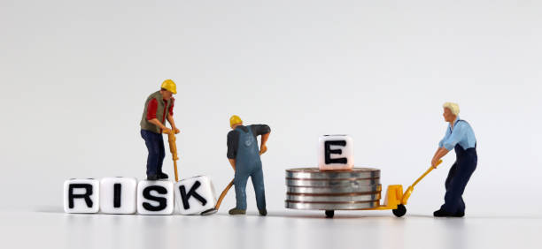 istock Miniature people who change cubes with RISK into RISE. Miniature man carrying E and coins in a cart. 1300438556