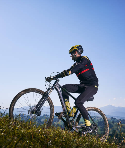 istock Joyful male cyclist riding bicycle uphill under blue sky. 1300438703