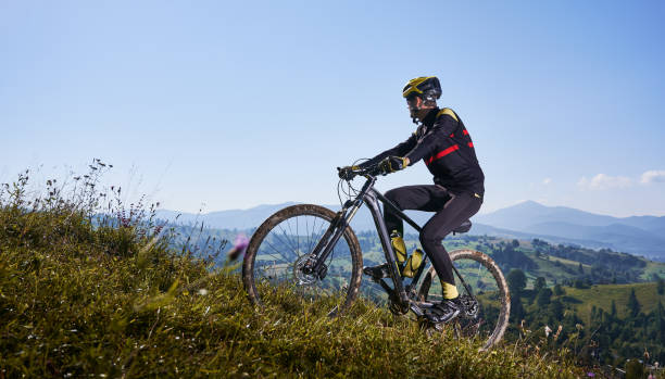 istock Joyful male cyclist riding bicycle uphill under blue sky. 1300438714