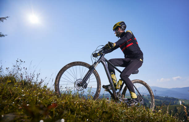 istock Joyful male cyclist riding bicycle uphill under blue sky. 1300438716