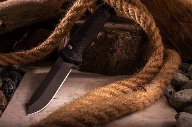 Photo of Knife on the background of stones and rope. Photo of a knife with a great depth of field.