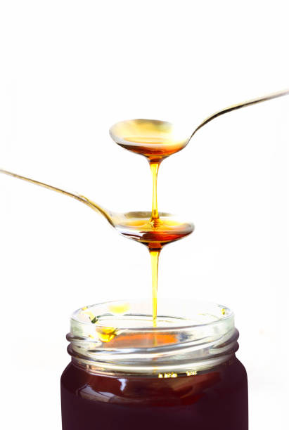 istock Honey drop in a spoon, glass bottle isolated on white background 1300442170