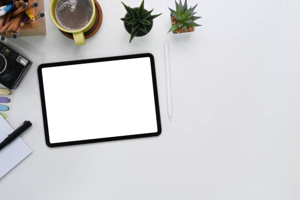 istock Top view of mockup digital tablet with empty screen, camera, coffee cup, notebook and copy space on photographer workspace. 1300443932