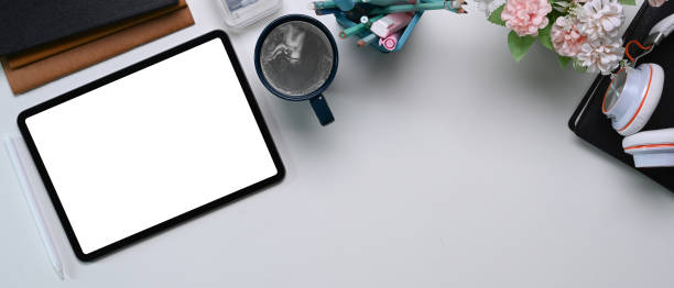 istock Overhead shot of white office desk with mock up digital tablet with empty screen, coffee cup and office supplies. 1300443979