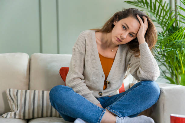 istock Depressed young woman on sofa at home 1300445371