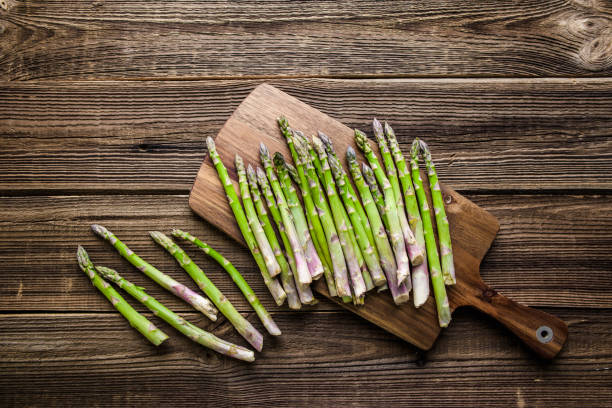 istock Green fresh asparagus on wooden board, top view 1300445565