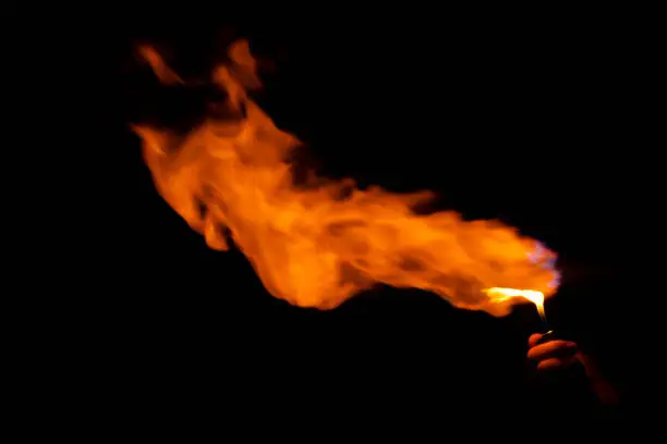 Hand holding burning gas lighters on dark background, Portable device used to create a flame, Close up