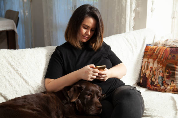 istock woman sitting on sofa with her labrador dog 1300453196