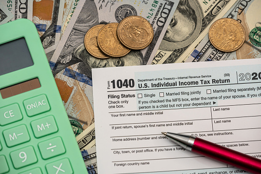 1040 Individual income tax return form with dollar bills and calculator. accounting concept