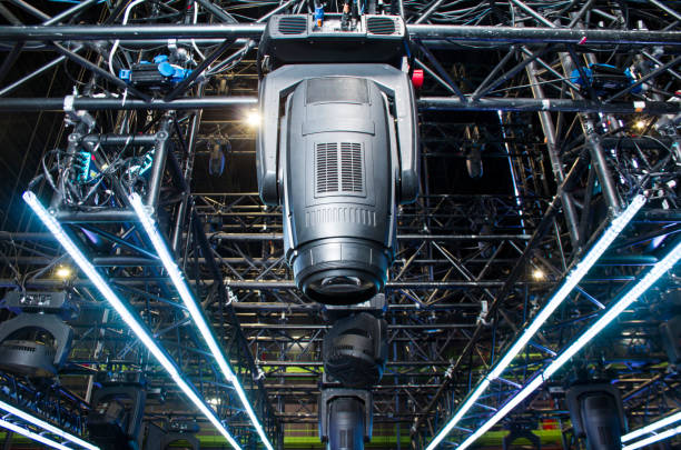 istock Moving head spotlight device is clamped on a rigging steel truss for lifting. Installation of professional stage light equipment for a concert. 1300460510
