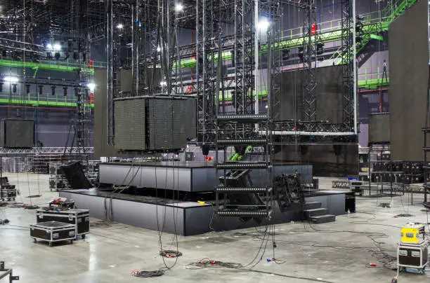 Installation of professional stage, sound, light and video equipment for a tv show. Led screens. Stage lighting equipment is clamped on a trusses. Line array speakers. Flight cases.