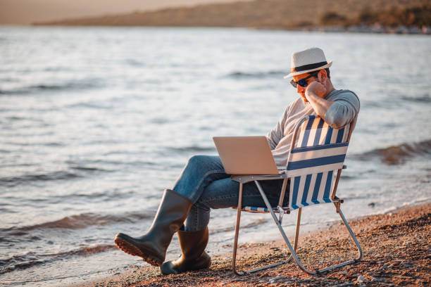 istock Freelance Young Man Working on Laptop on the Beach 1300462928